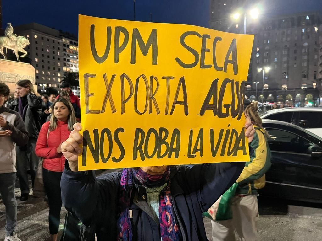 Mielenosoittaja kaupungin kadulla kyltin kanssa: "UPM seca exporta agua, no roba la vída"