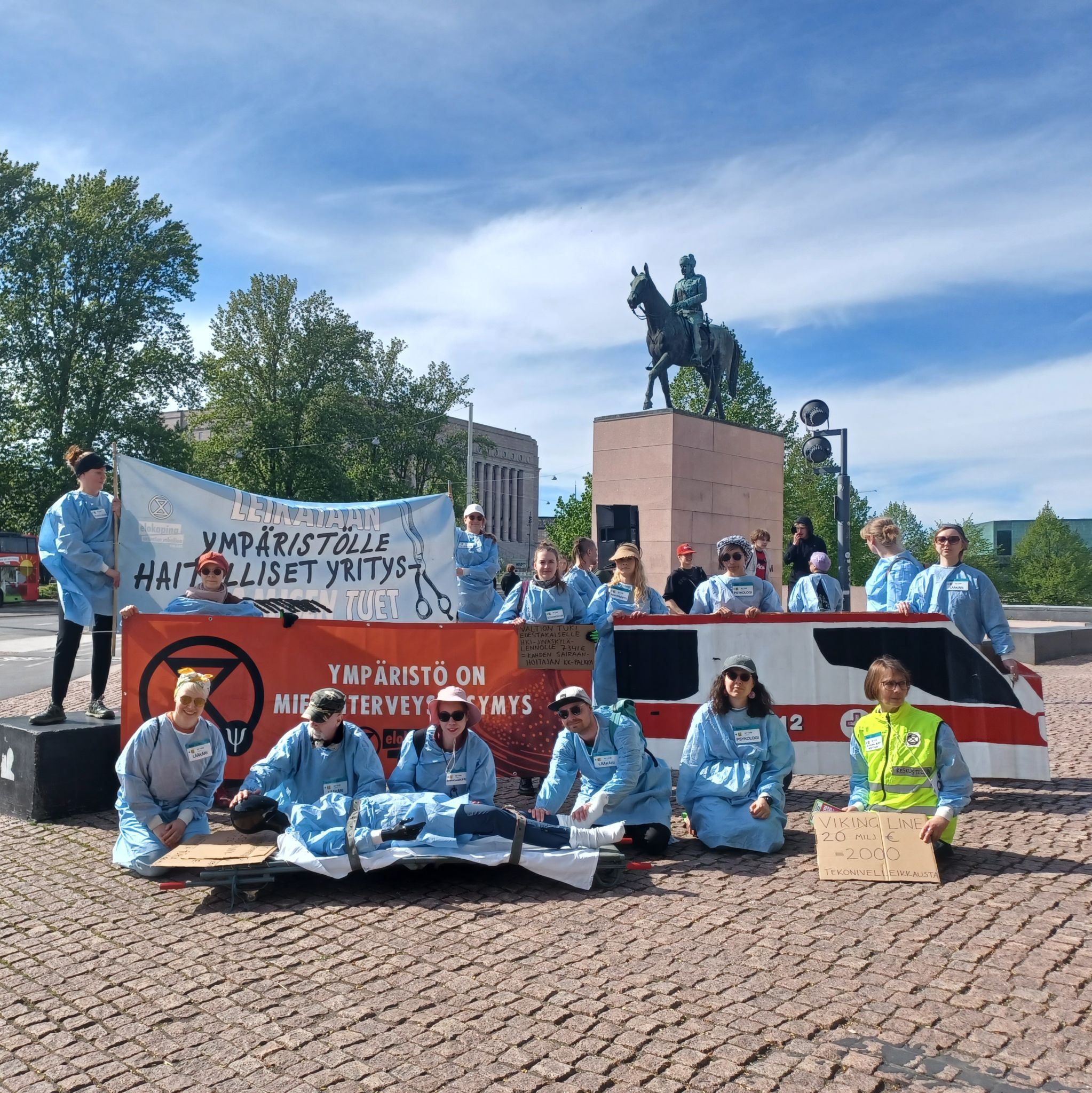 Kuva Leikkausvirhe-mielenosoituksesta 26.5.2025. Kuvassa mm. banneri tekstillä: "Ympäristö on mielenterveyskysymys".